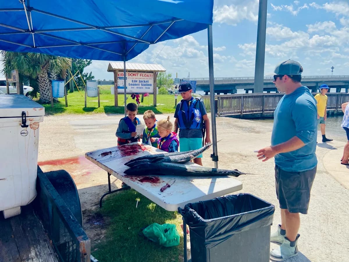 Young anglers gathered around the official weigh-in table with their Kingfish catch at the dock