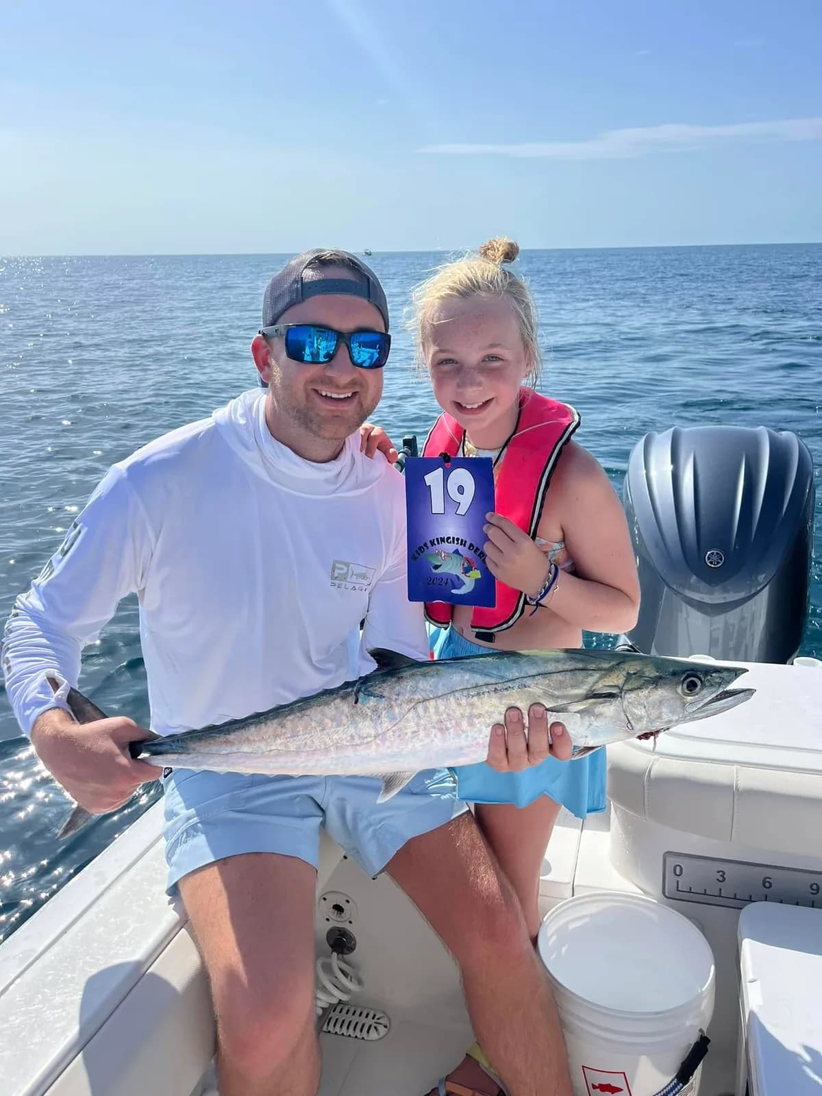 Adult and young girl proudly holding a Kingfish at the tournament with number 19 tag