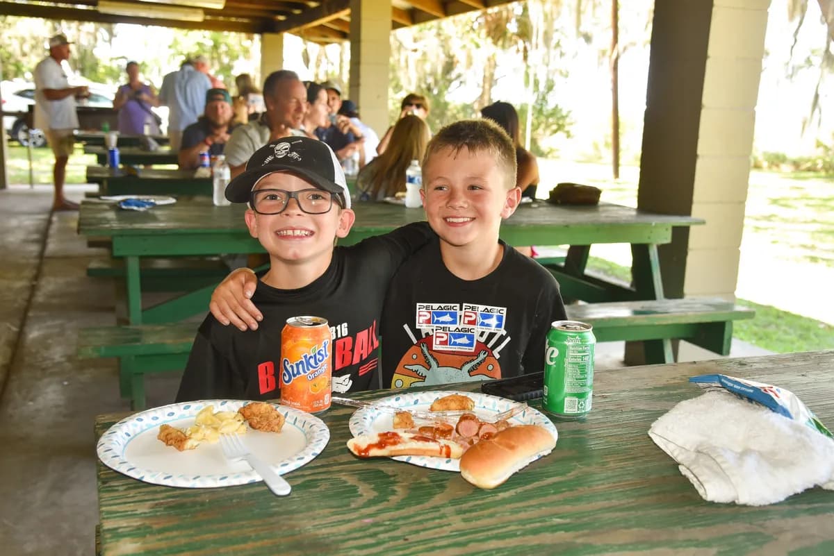 Two young anglers smiling together at a picnic table enjoying the post-tournament awards cookout