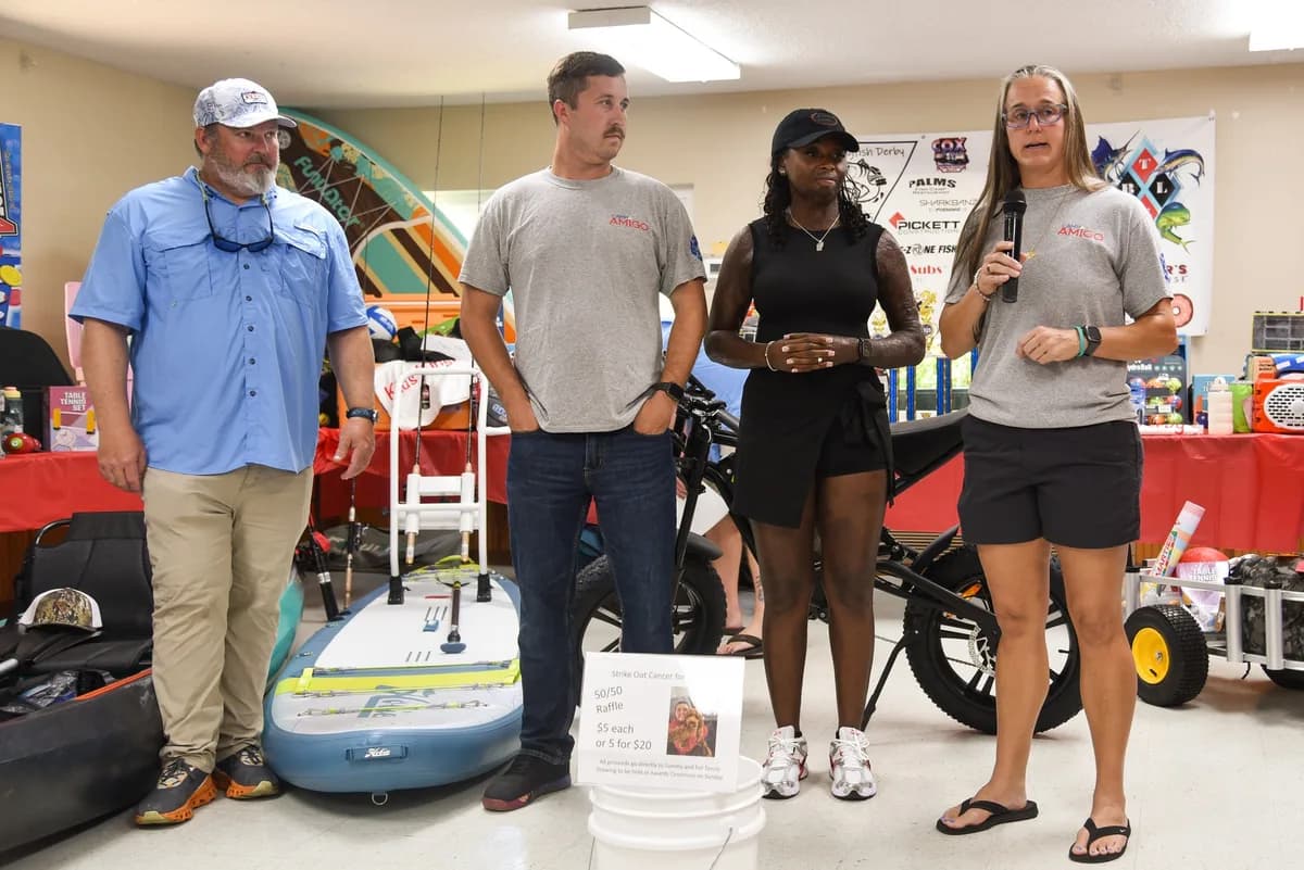 Tournament organizers and sponsors speaking at the awards ceremony with a paddleboard prize on display