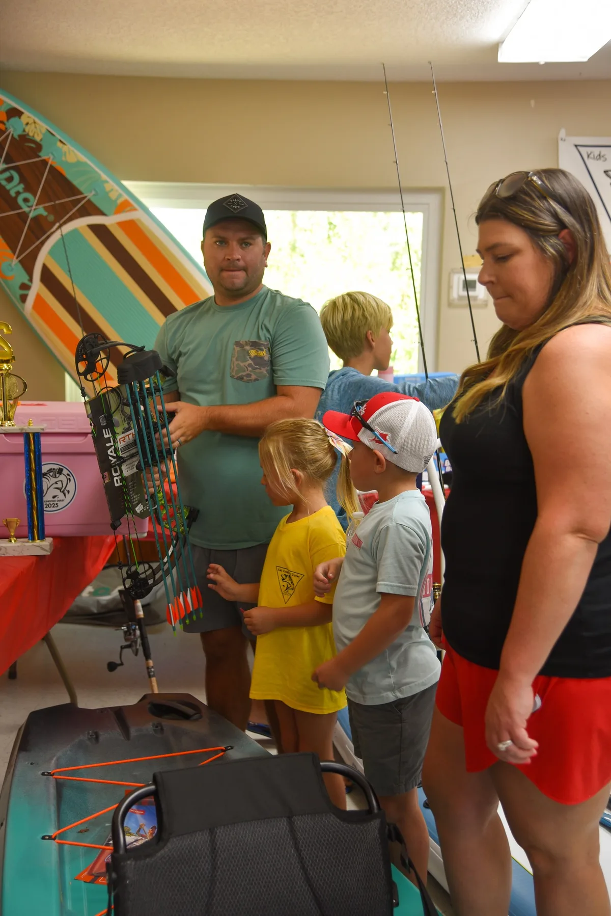 Family browsing prize items including a compound bow at the awards cookout prize table